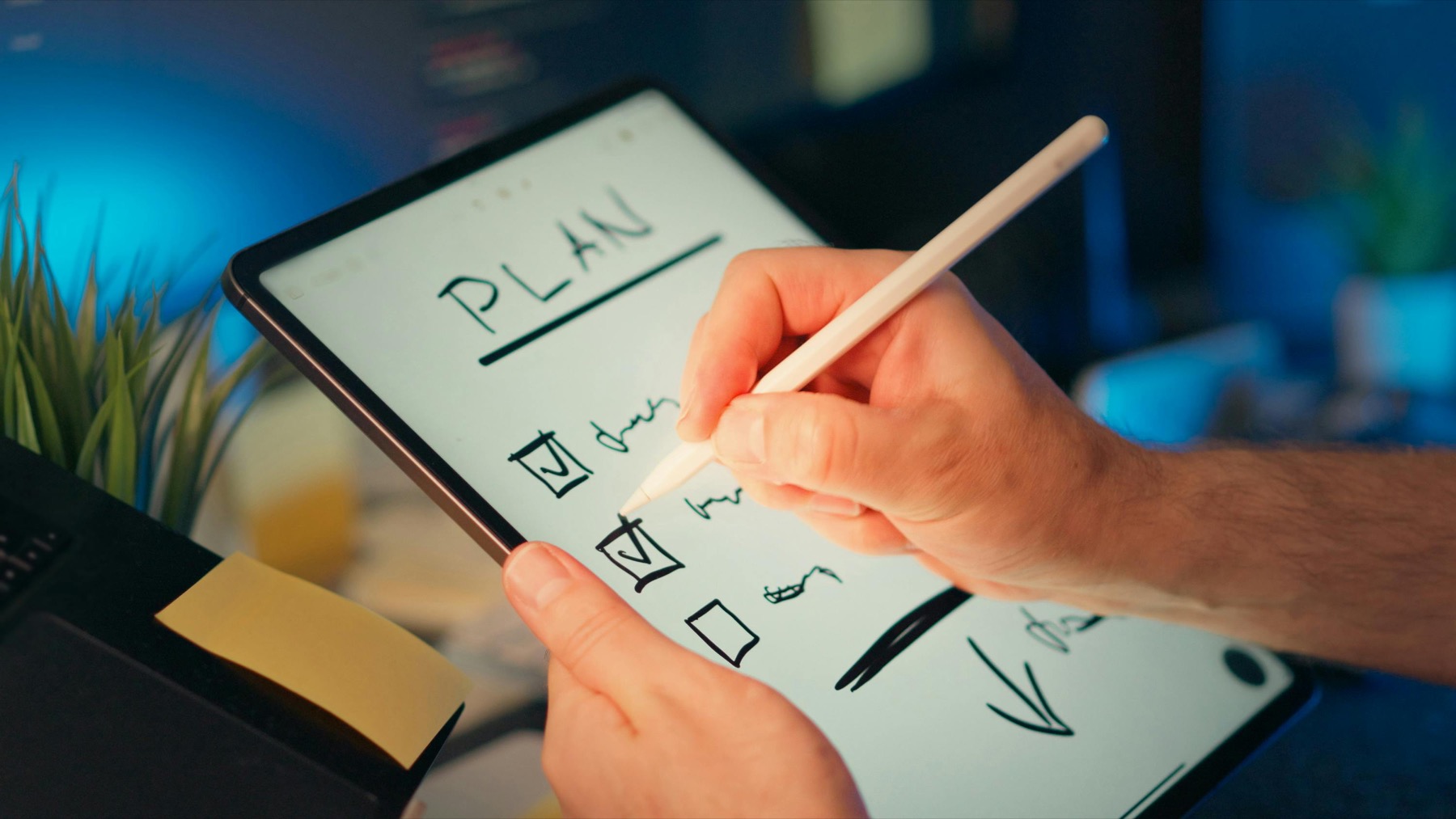 A hand using a stylus on a tablet checklist during a focused planning session.