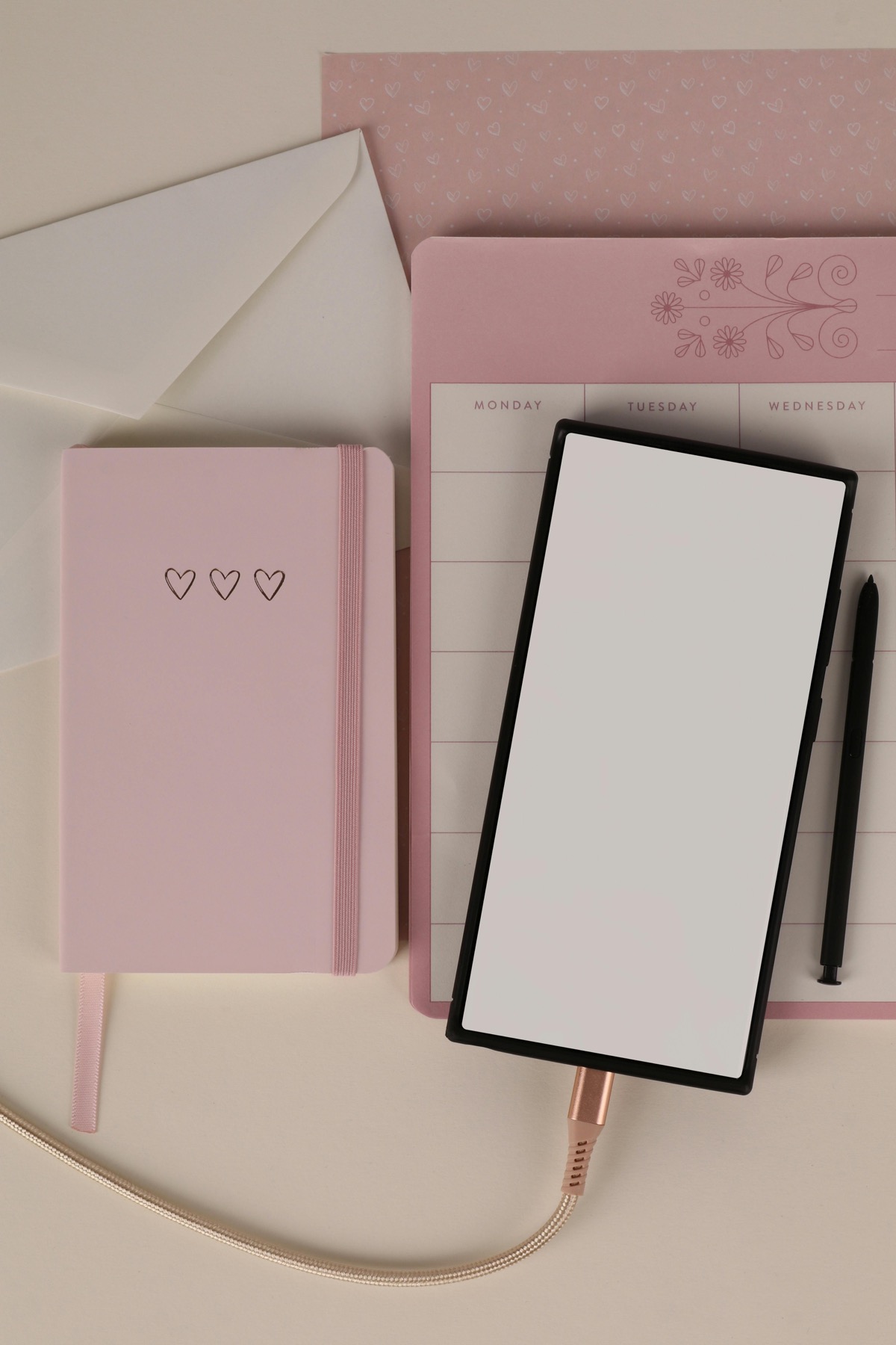 A pink digital planning flat lay with tablet, notebook, and weekly planner stationery.
